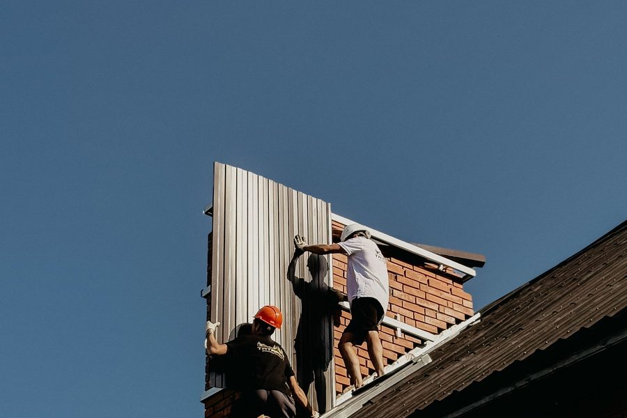 Workers fitting metal roof panels